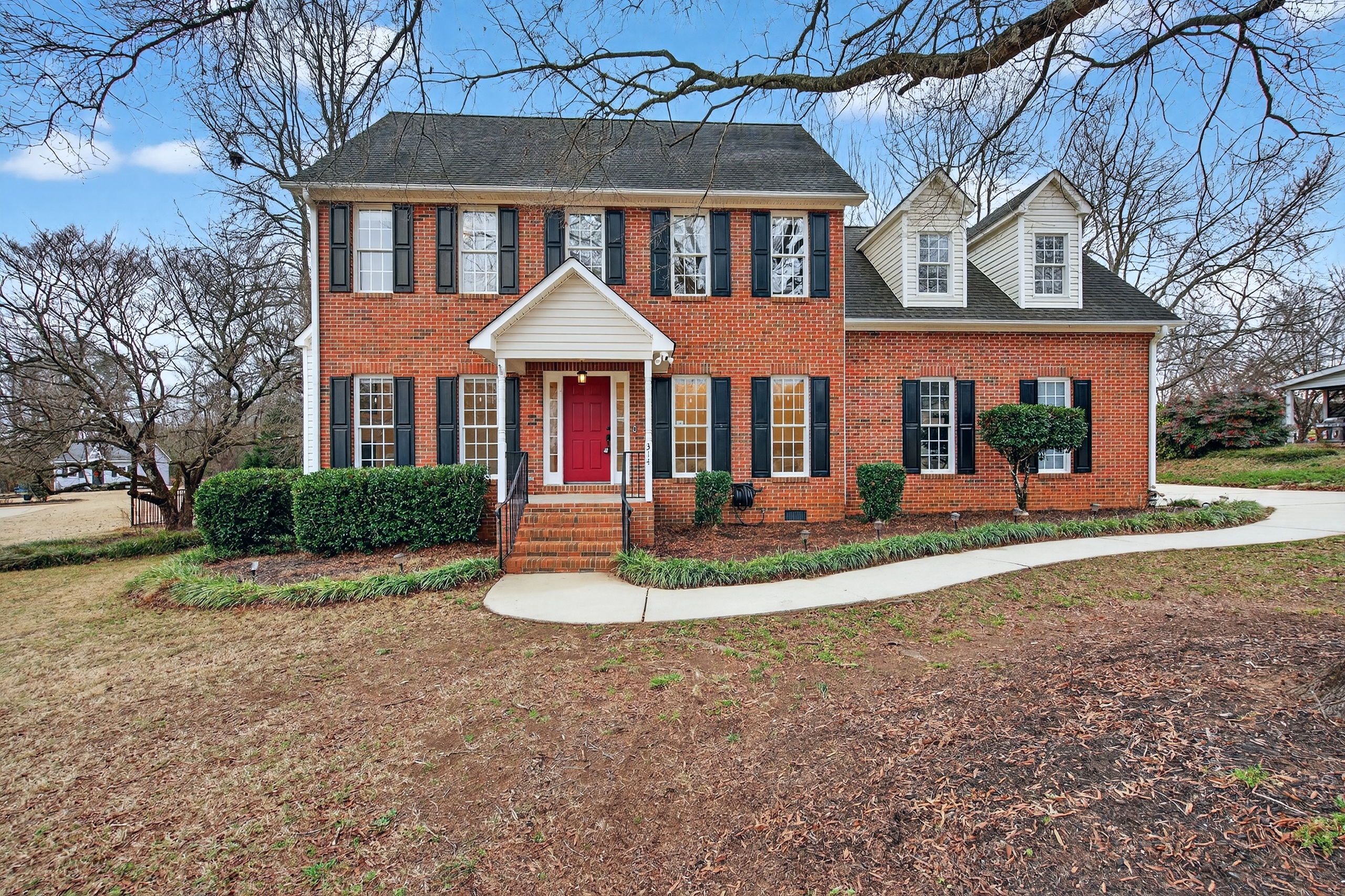 Curb appeal of a Spartanburg South Carolina home with brick steps and a welcoming red door, representing real estate market value in 2026.