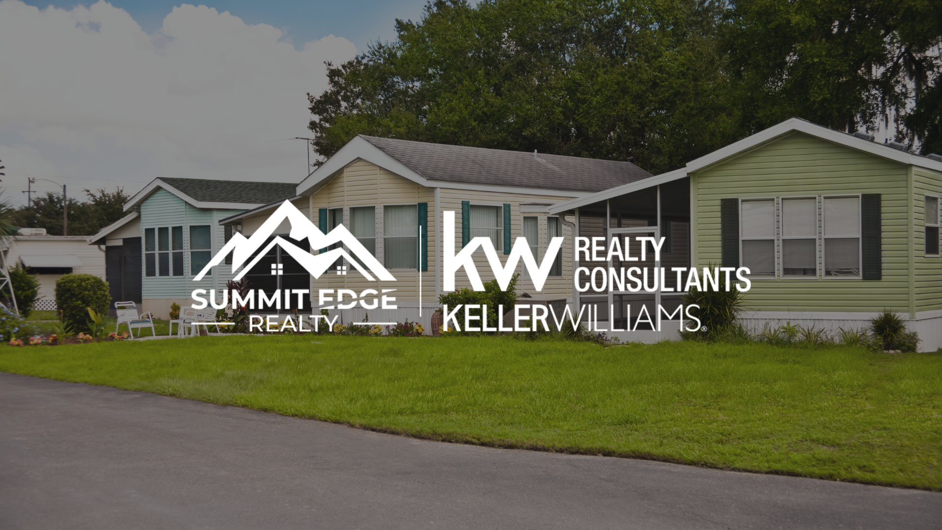 A Clark County, IN, community of manufactured homes with beige and green exteriors, small porches, and front gardens with vibrant flowers and shrubs, set on a green lawn under a partly cloudy sky, overlaid with the Summit Edge Realty and KW Realty Consultants Keller Williams logo in white.