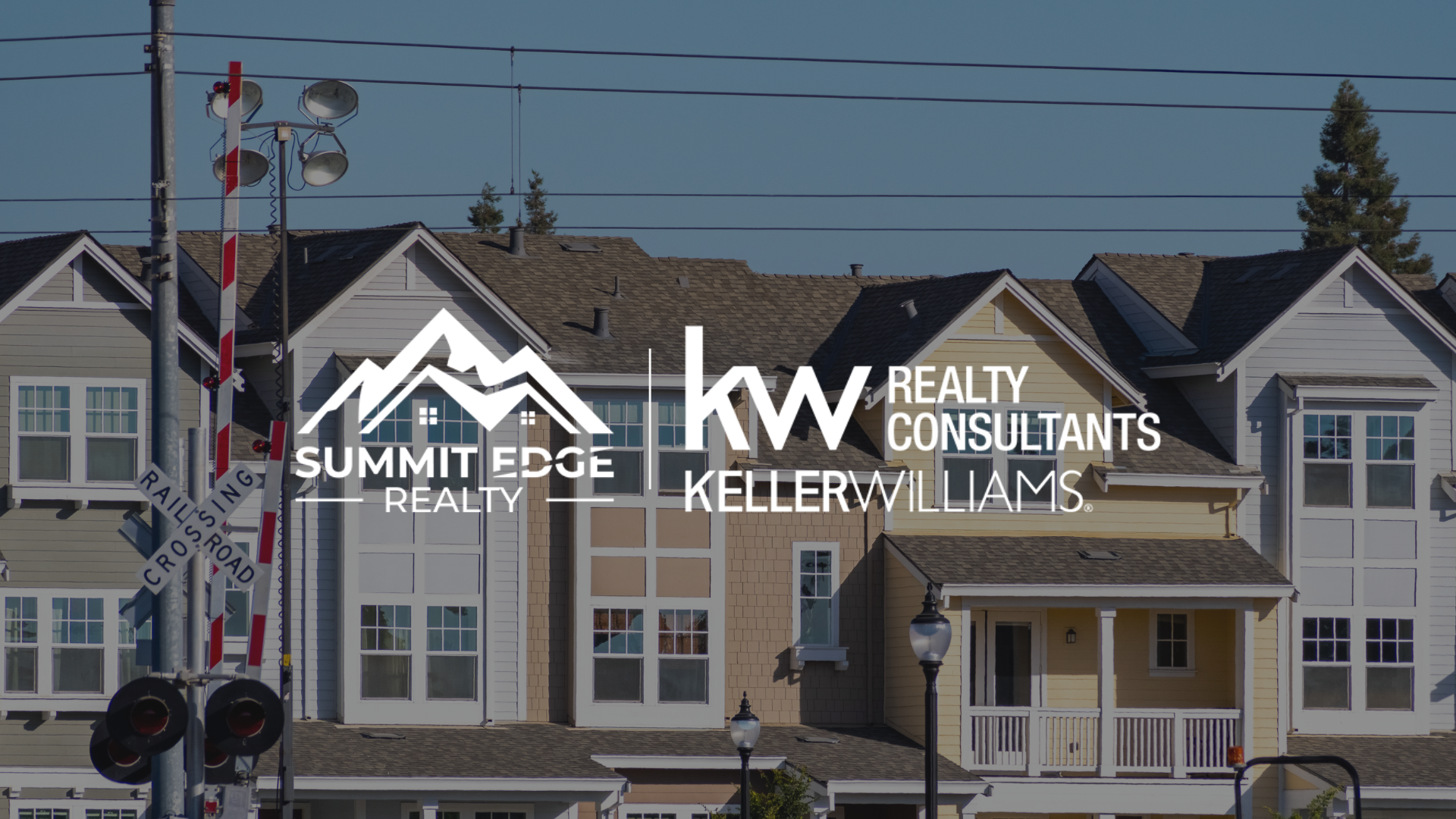 A Clark County, IN, multifamily home residential scene with homes in gray, beige, and yellow tones, large windows, and a nearby railroad crossing signal, overlaid with the Summit Edge Realty and KW Realty Consultants Keller Williams logo in white.