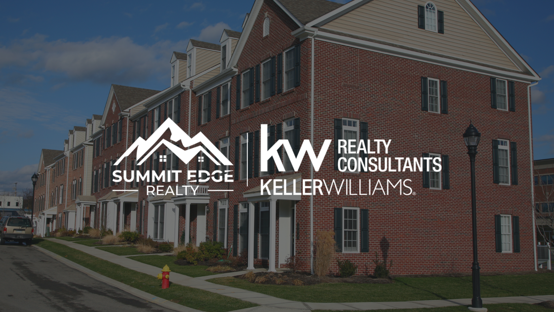 Exterior of colonial apartment style condos with Summit Edge Realty logo in foreground