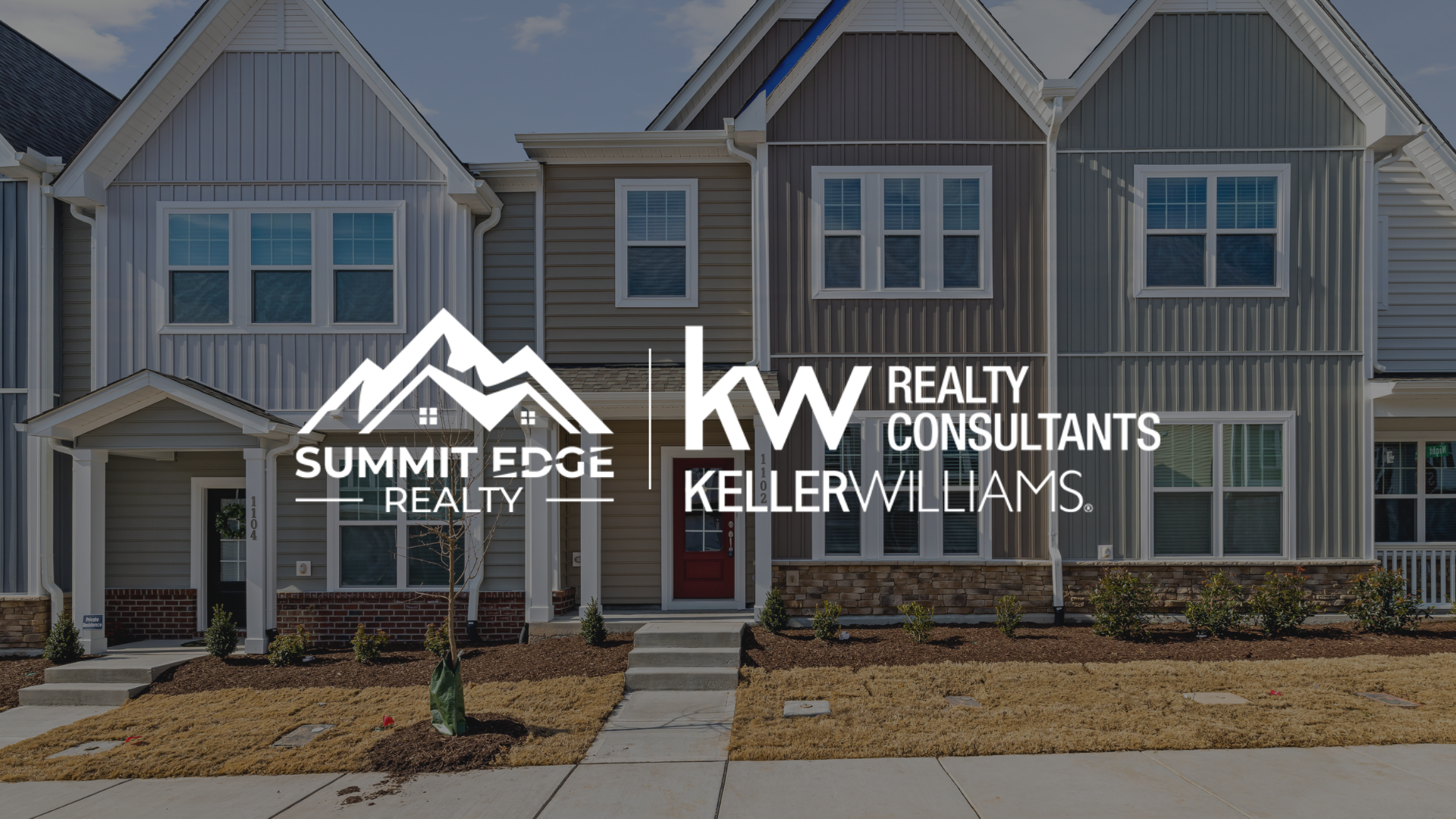A Harrison County, IN, multifamily home with a beige and gray duplex, a shared driveway, and a front garden with blooming flowers, set in a scenic tree-lined area, overlaid with the Summit Edge Realty and KW Realty Consultants Keller Williams logo in white.
