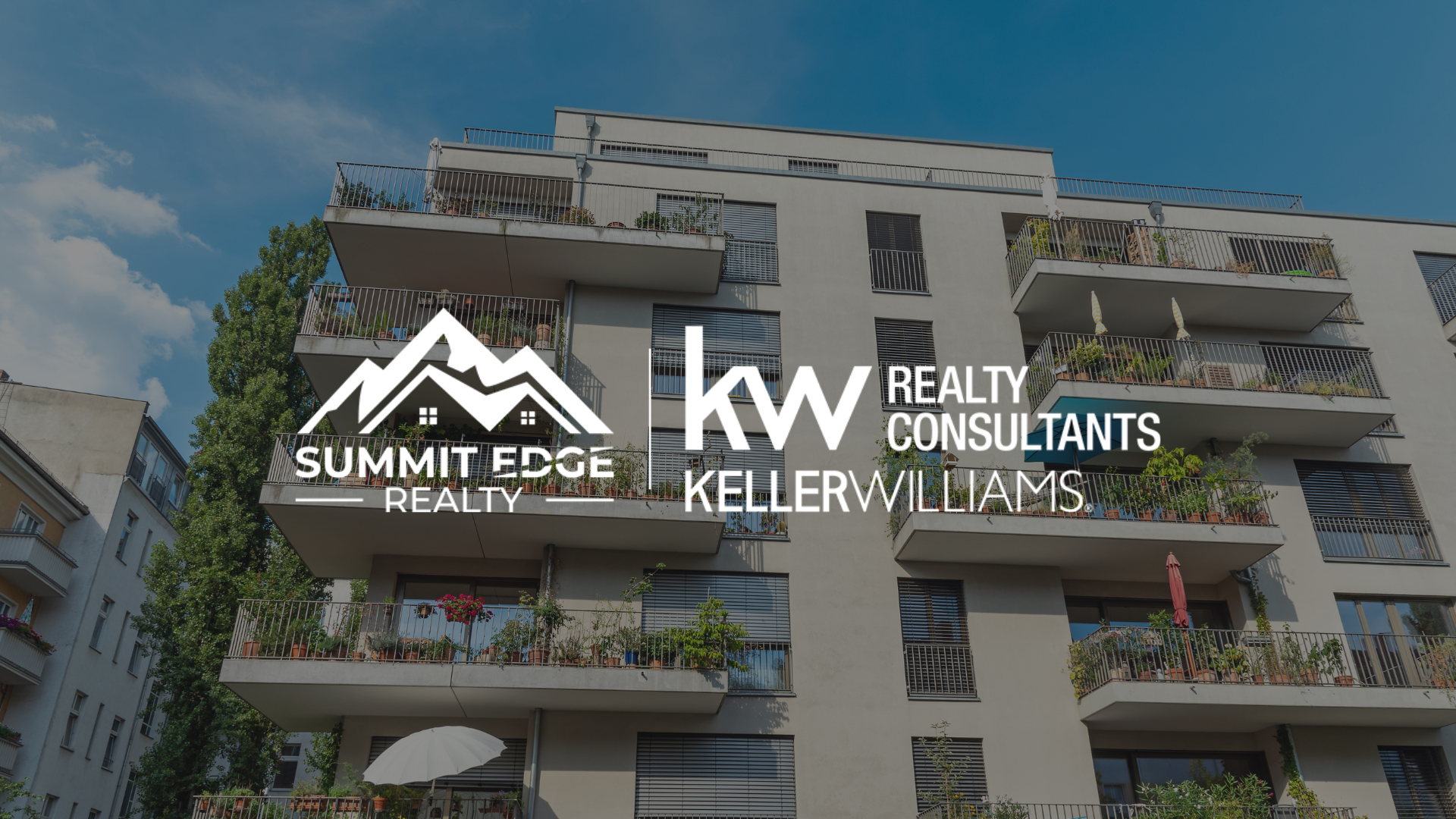 Exterior view of a Harrison County, IN, multifamily housing complex with a beige exterior, featuring balconies with lush plants and umbrellas, surrounded by trees, branded with the Summit Edge Realty and KW Realty Consultants Keller Williams logo in white.