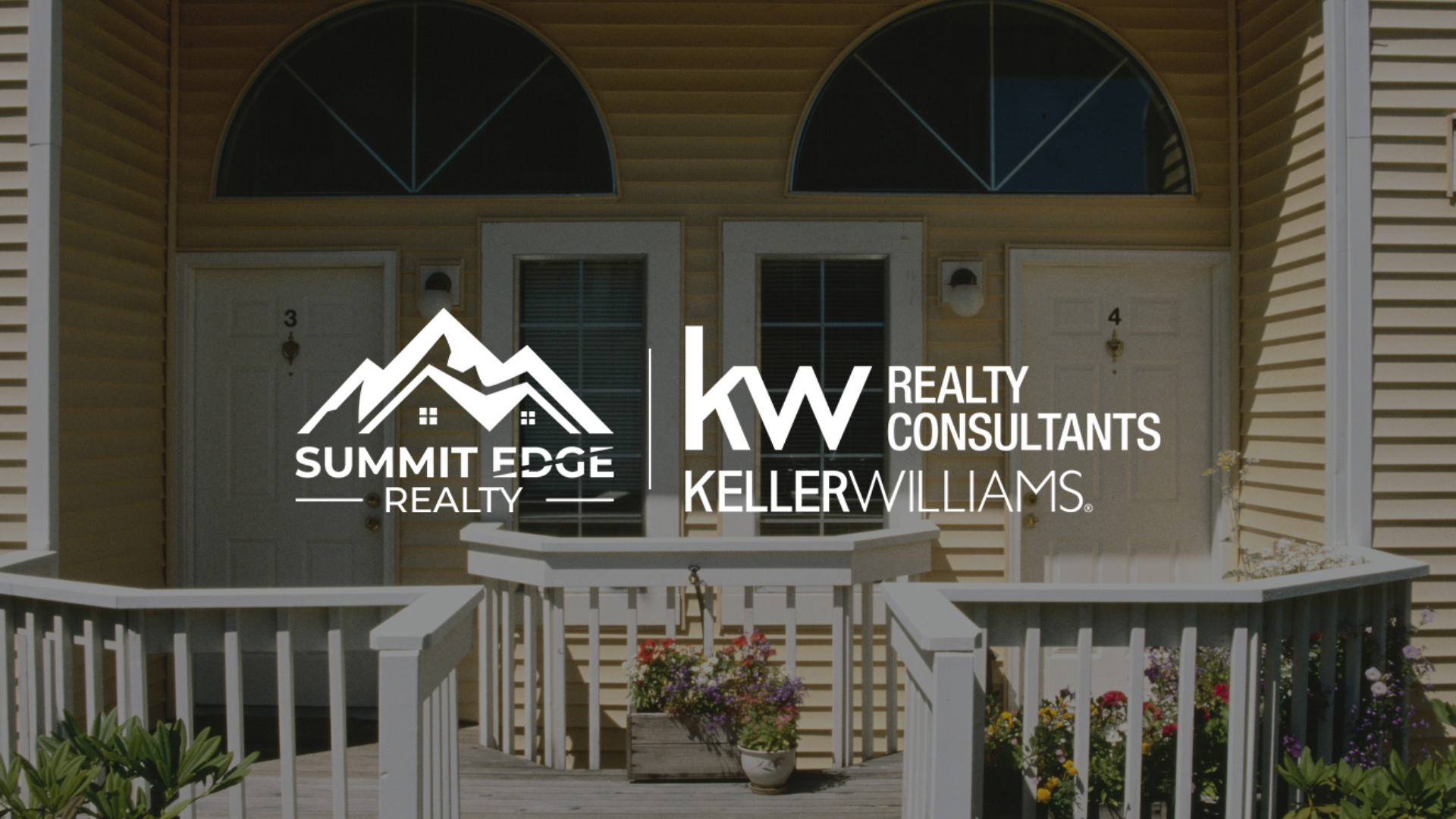 A charming multifamily house in Floyd County, IN, with gray and white siding, a shared driveway, and a small front garden with blooming flowers, overlaid with the Summit Edge Realty and KW Realty Consultants Keller Williams logo in white text.