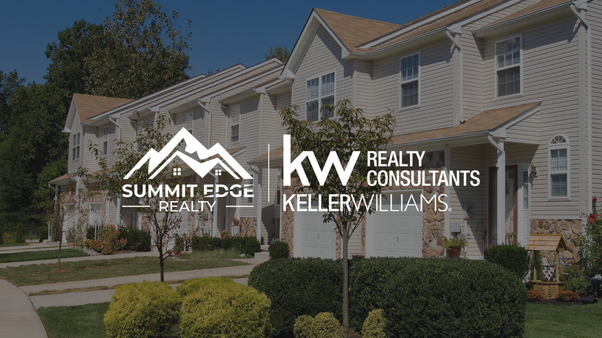 Exterior view of multifamily houses in Floyd County, IN, with beige exteriors, garages, and lush green lawns with shrubs, branded with the Summit Edge Realty and KW Realty Consultants Keller Williams logo in white.