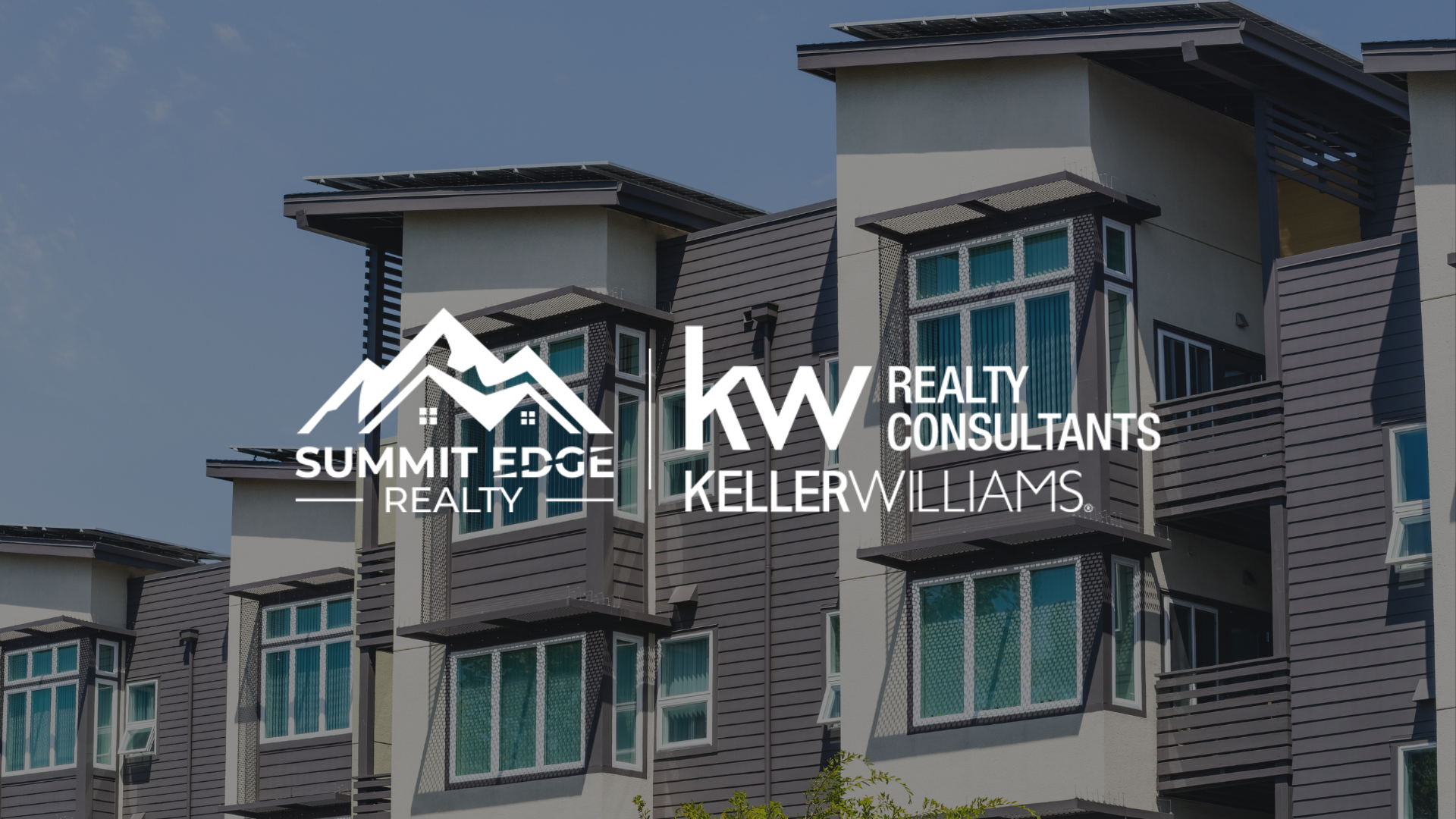 Exterior view of a Louisville, KY, multifamily housing building with red brick and beige siding, spacious windows, and a courtyard with a garden area, branded with the Summit Edge Realty and KW Realty Consultants Keller Williams logo in white.