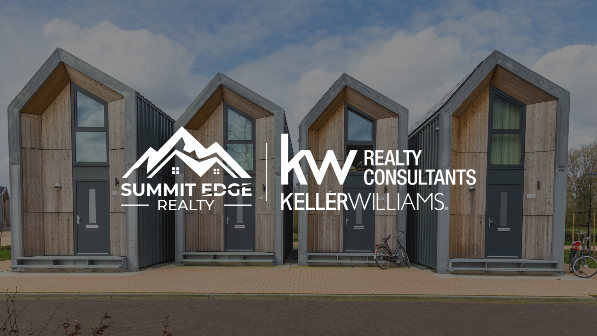 A Clark County, IN, community of tiny homes with wooden and gray exteriors, black-framed windows, and gray doors, set on a paved path with bicycles beside under a partly cloudy sky, overlaid with the Summit Edge Realty and KW Realty Consultants Keller Williams logo in white.