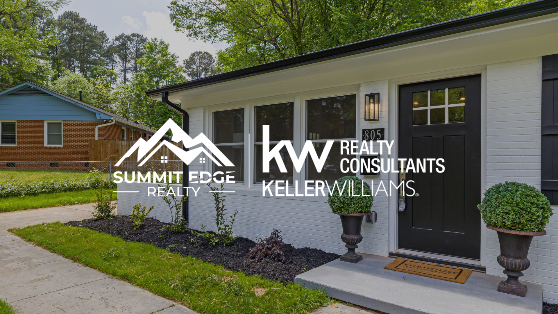 A white single family home with black shutters and a front porch, featuring the Summit Edge Realty and Keller Williams Realty Consultants logo in the foreground.