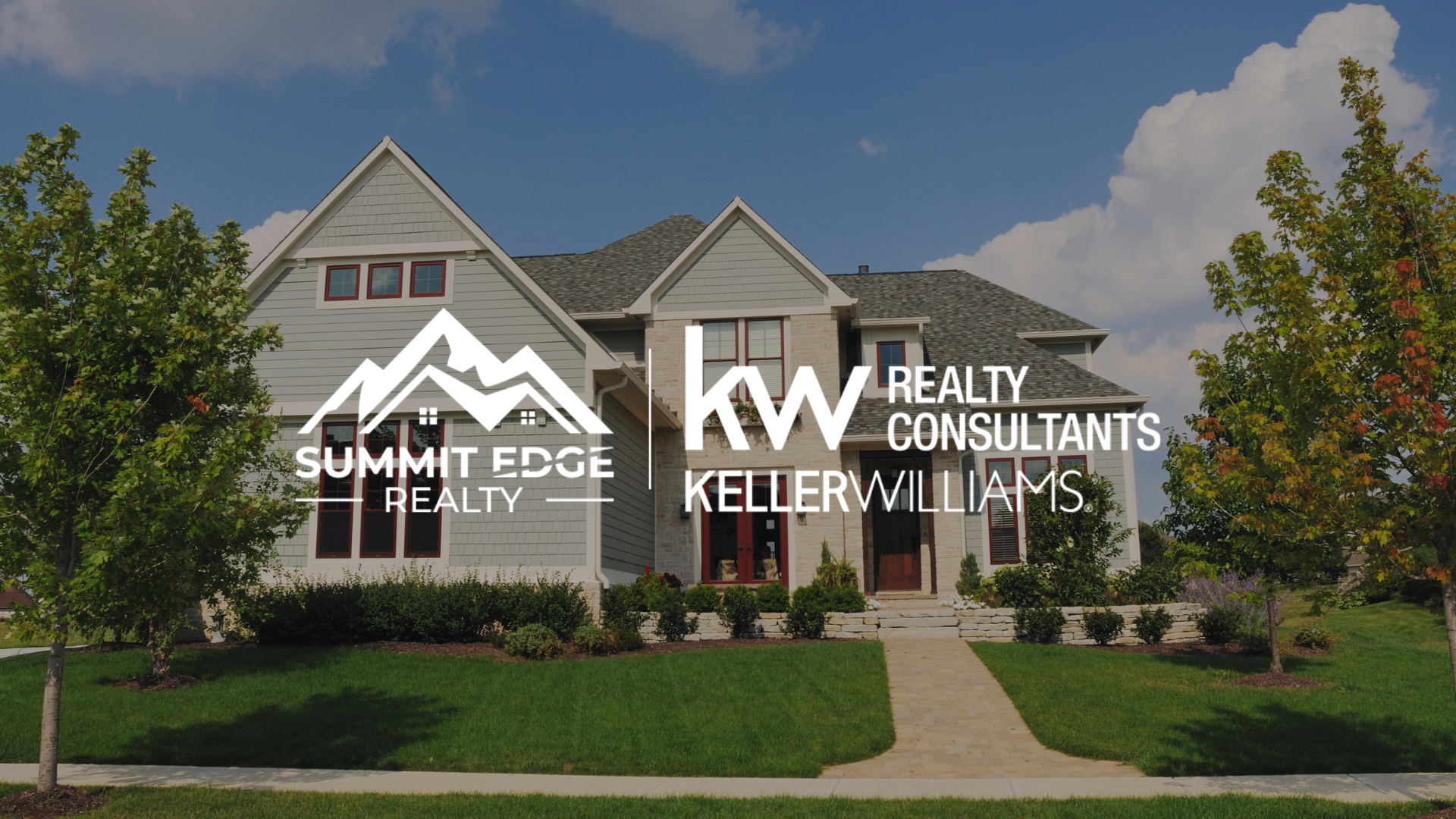 A large two-story single family home with a gray exterior and red-framed windows, featuring the Summit Edge Realty and Keller Williams Realty Consultants logo in the foreground.
