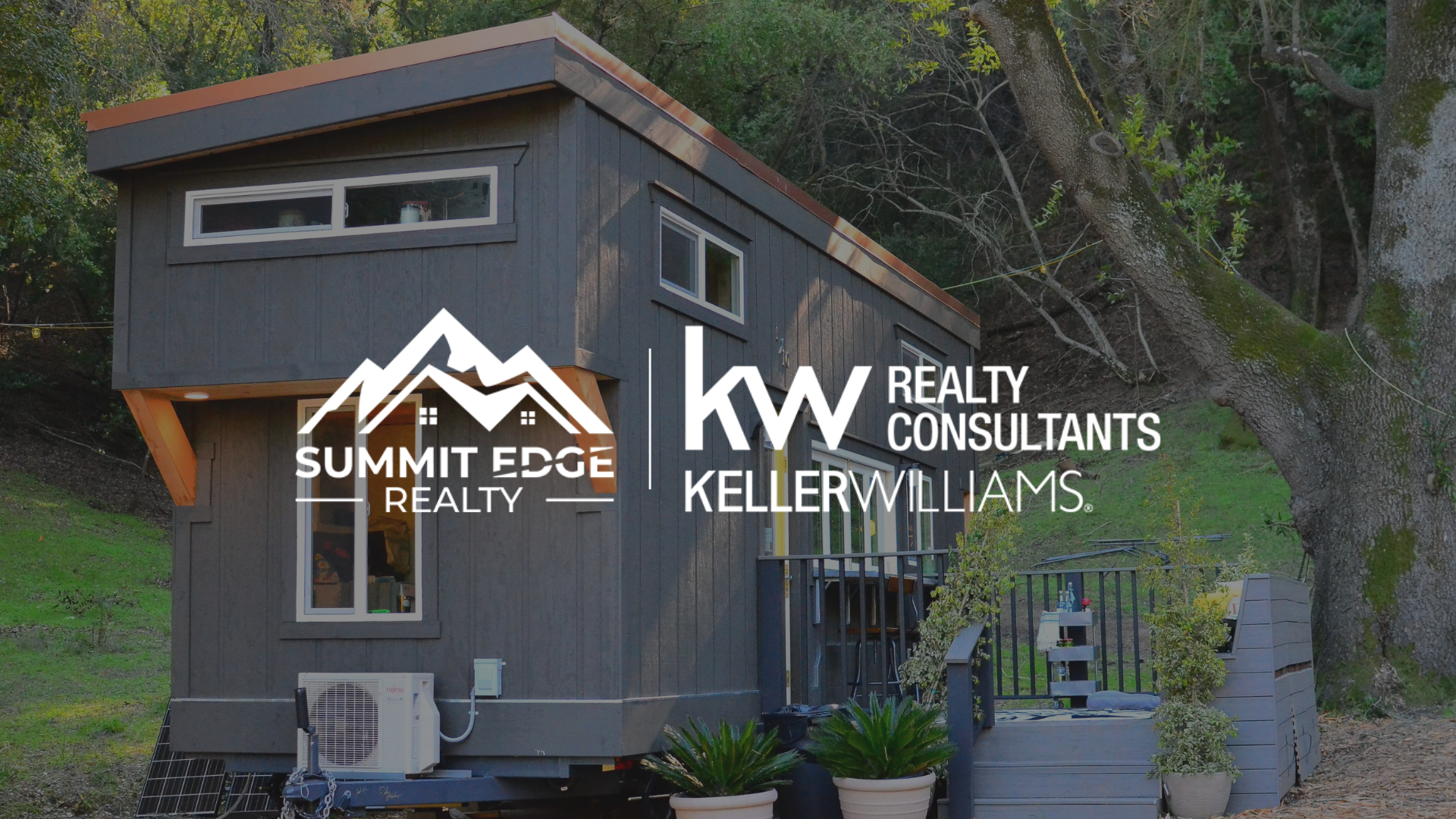 A Harrison County, Indiana, tiny residence with a white metal exterior, a flat black roof, and a glass door, including a small patio with chairs, set on a gravel site surrounded by pine trees under a clear sky, overlaid with the Summit Edge Realty and KW Realty Consultants Keller Williams logo in white.