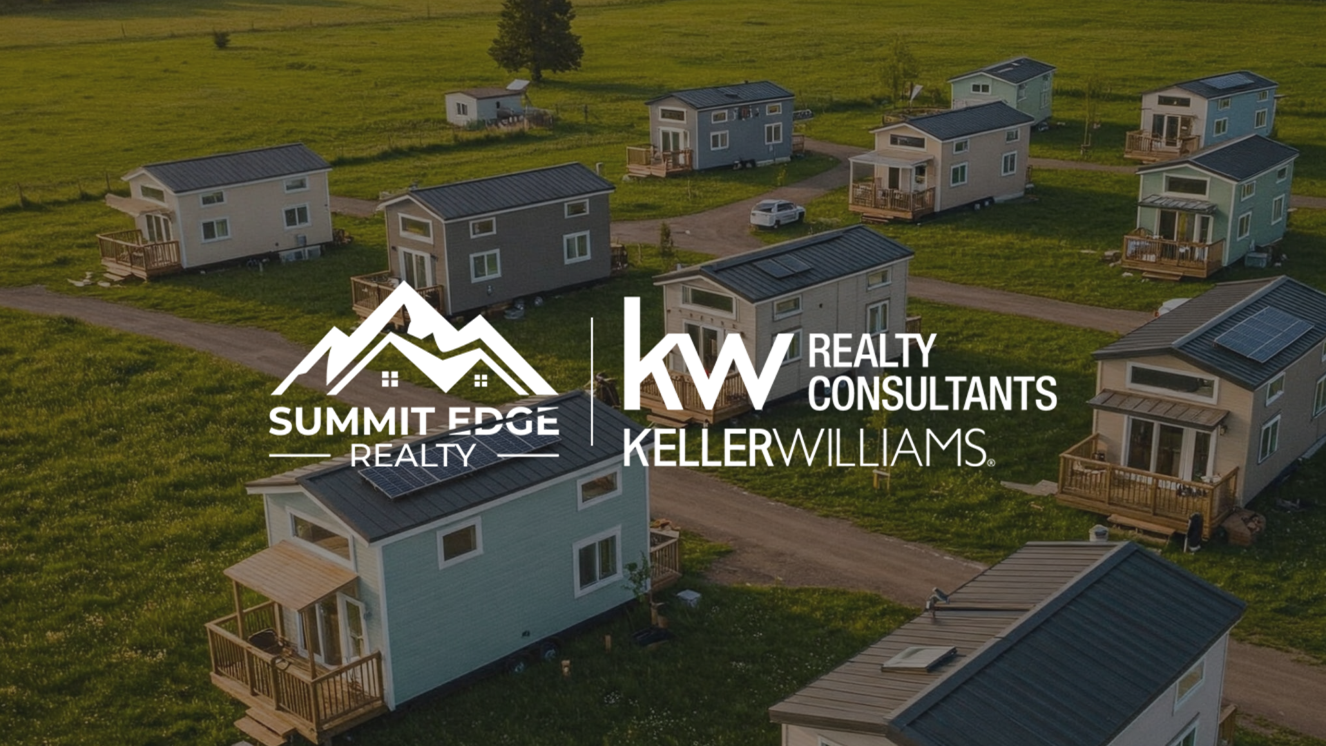 A stylish tiny home in Harrison County, Indiana, with a dark blue wooden exterior, a pitched red roof, and a large front window, featuring a small garden bed with flowers, set on a grassy lot with oak trees in the background under a clear sky, overlaid with the Summit Edge Realty and KW Realty Consultants Keller Williams logo in white text.