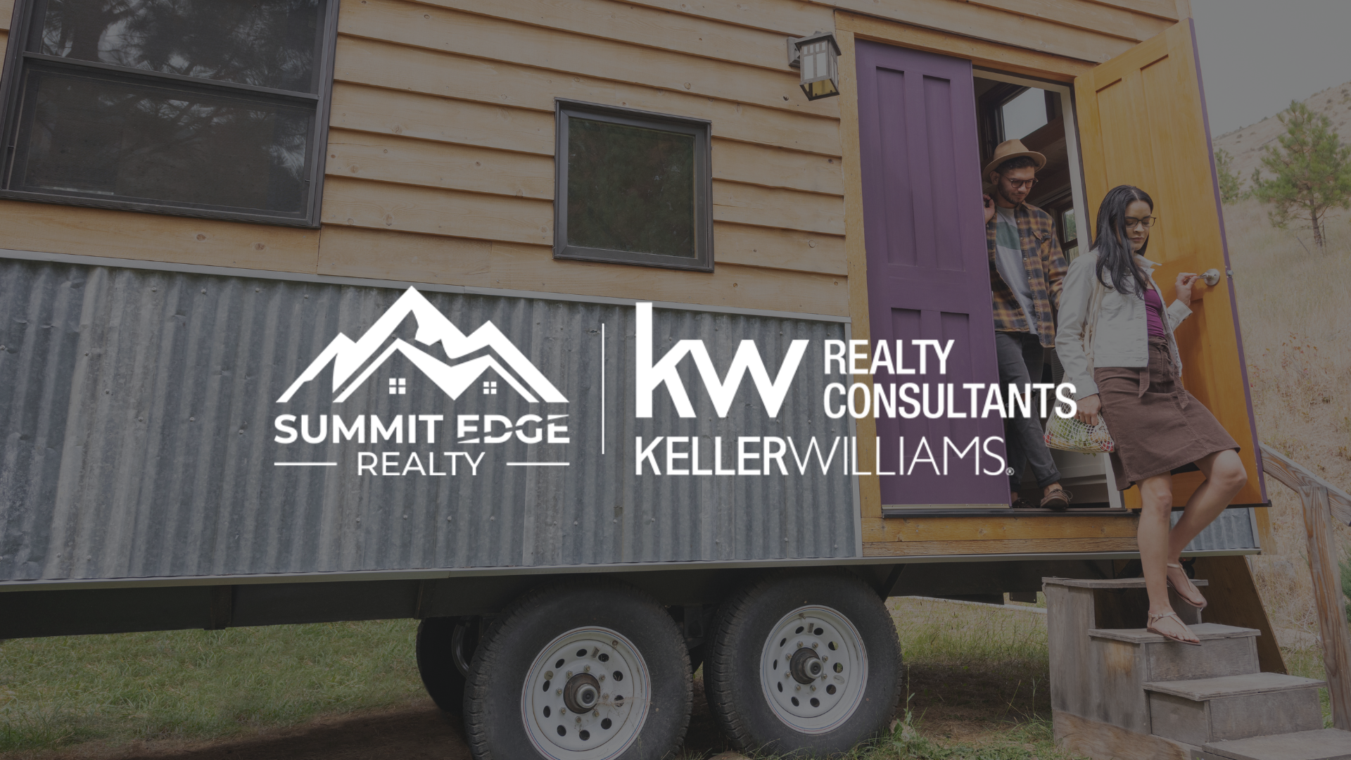 Exterior view of a Clark County, IN, tiny house on wheels with a wooden facade, large windows, and a purple door, with a wooden staircase and two people exiting, situated on a grassy area with trees in the background, branded with the Summit Edge Realty and KW Realty Consultants Keller Williams logo in white.