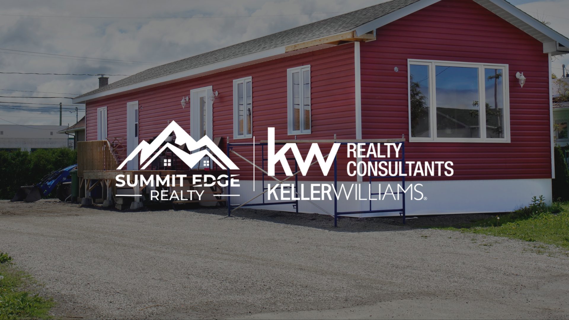 A cozy manufactured home in Floyd County, IN, with a gray exterior, a small covered porch, and a well-maintained lawn with flowerbeds, set against a backdrop of trees under a clear morning sky, overlaid with the Summit Edge Realty and KW Realty Consultants Keller Williams logo in white text.
