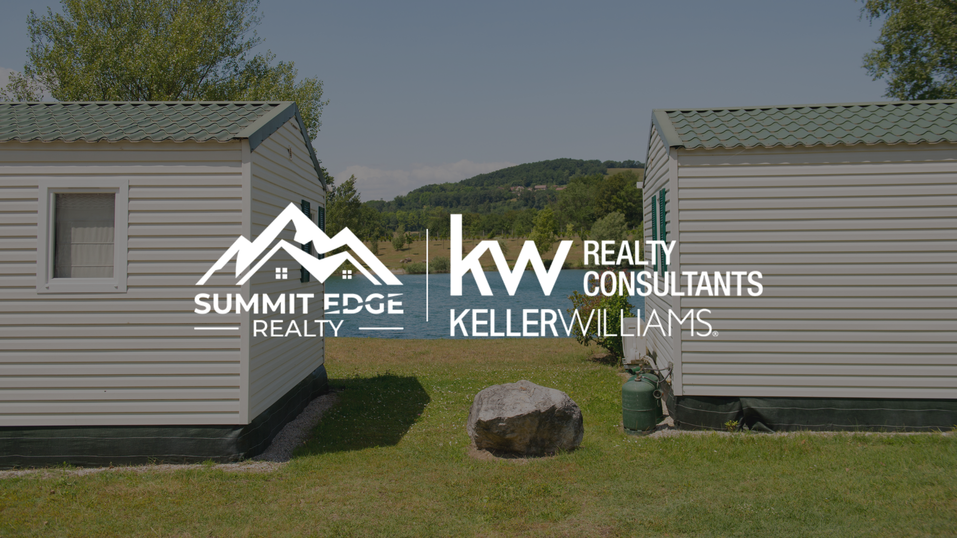 Exterior view of a Floyd County, IN, manufactured home featuring a gray facade, a covered front porch with wooden steps, and a neat lawn with a small flower garden, set against a backdrop of trees under a partly cloudy sky, branded with the Summit Edge Realty and KW Realty Consultants Keller Williams logo in white.
