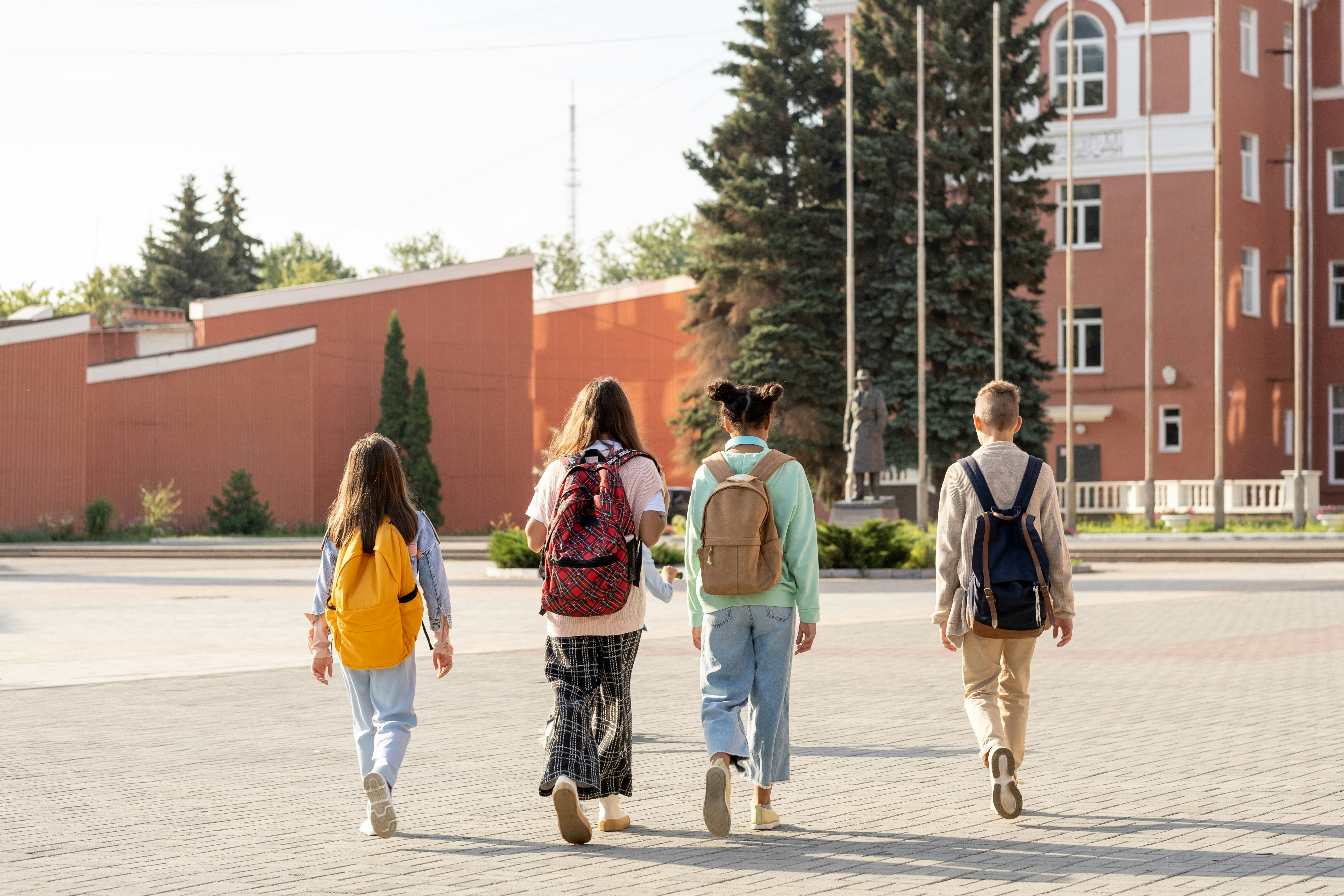 Kids with backpacks walking toward school building