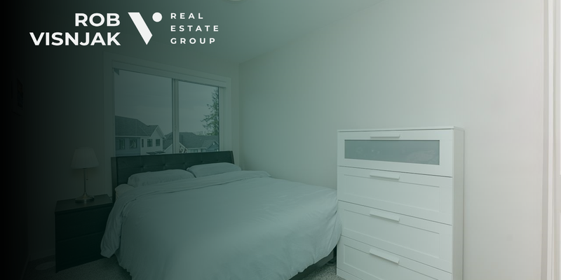 Bedroom with a grey upholstered bed and a white dresser in a Surrey townhome