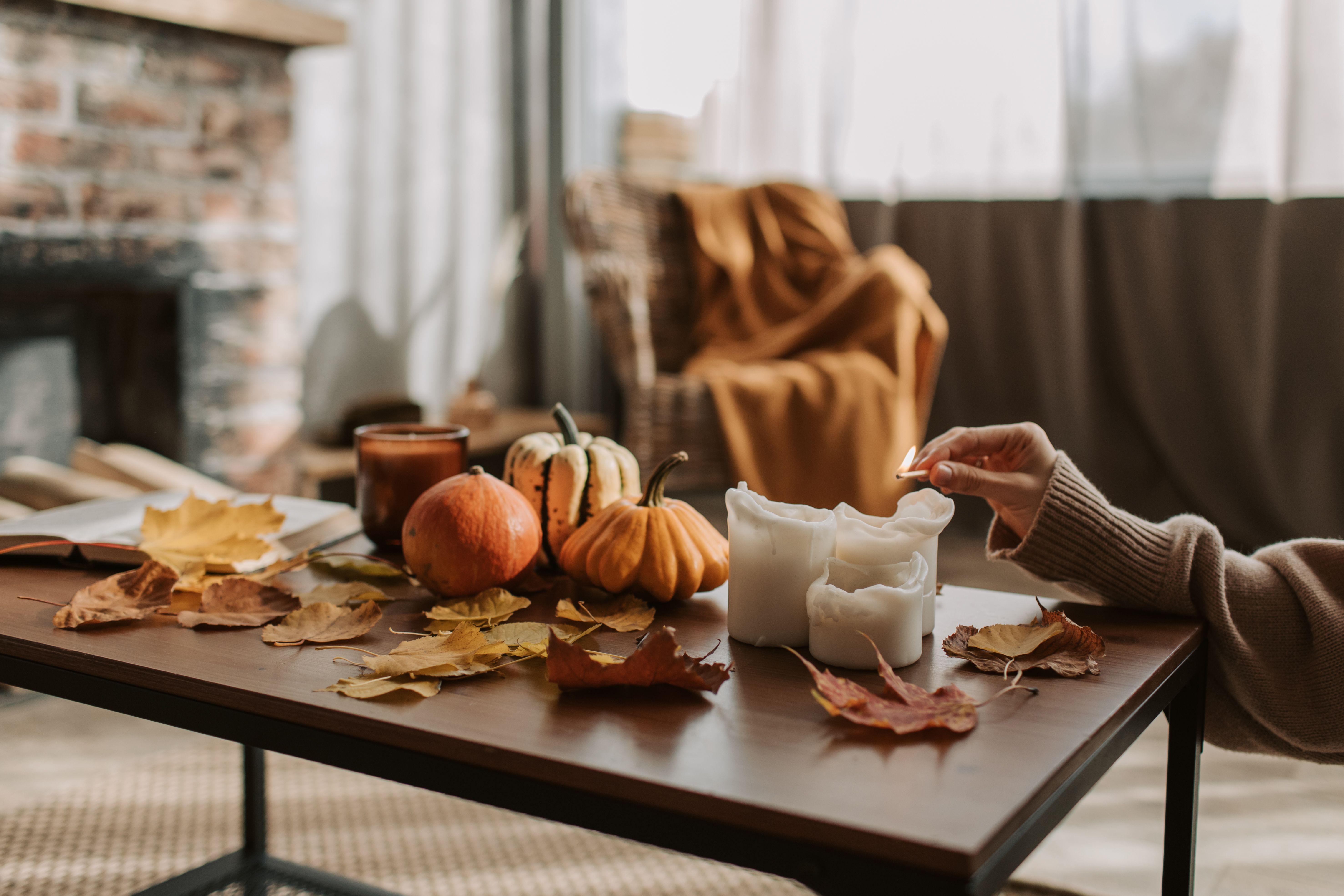 Cozy fall home with pumpkins, candles, autumn leaves and a warm blanket