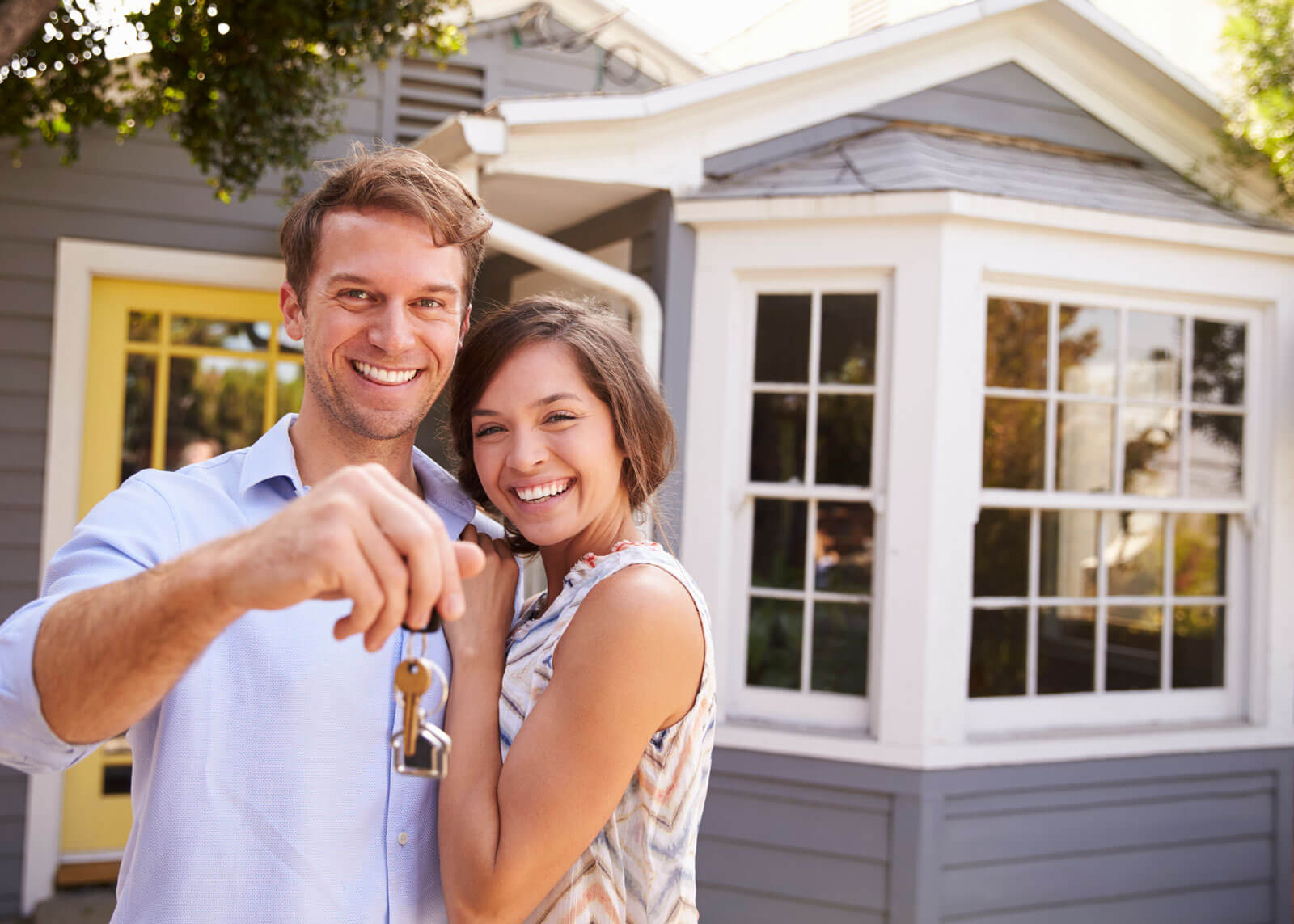young couple holding house keys on front porch