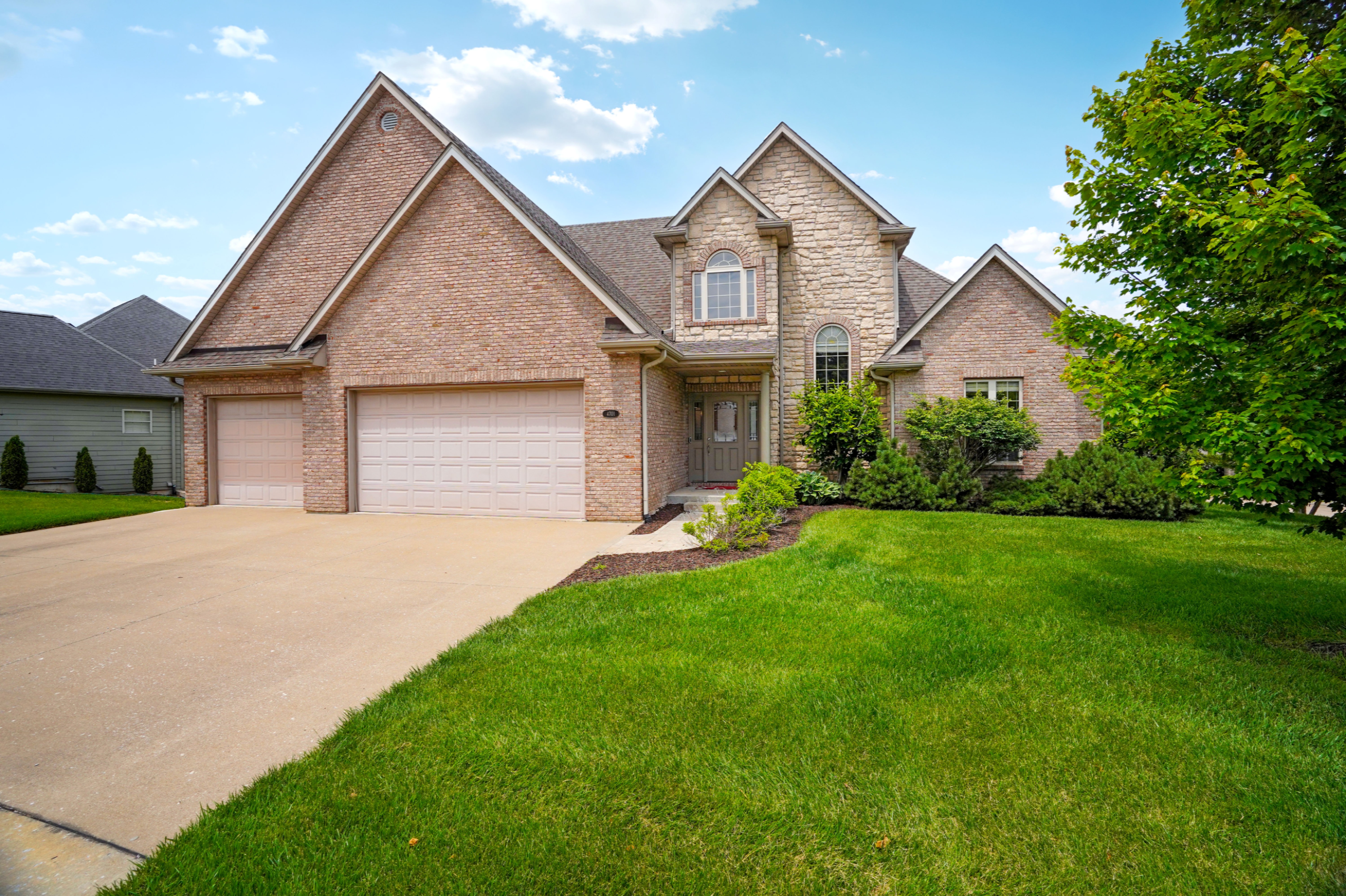 Brick and stone home with a three-car garage and landscaped lawn in Columbia, Missouri.