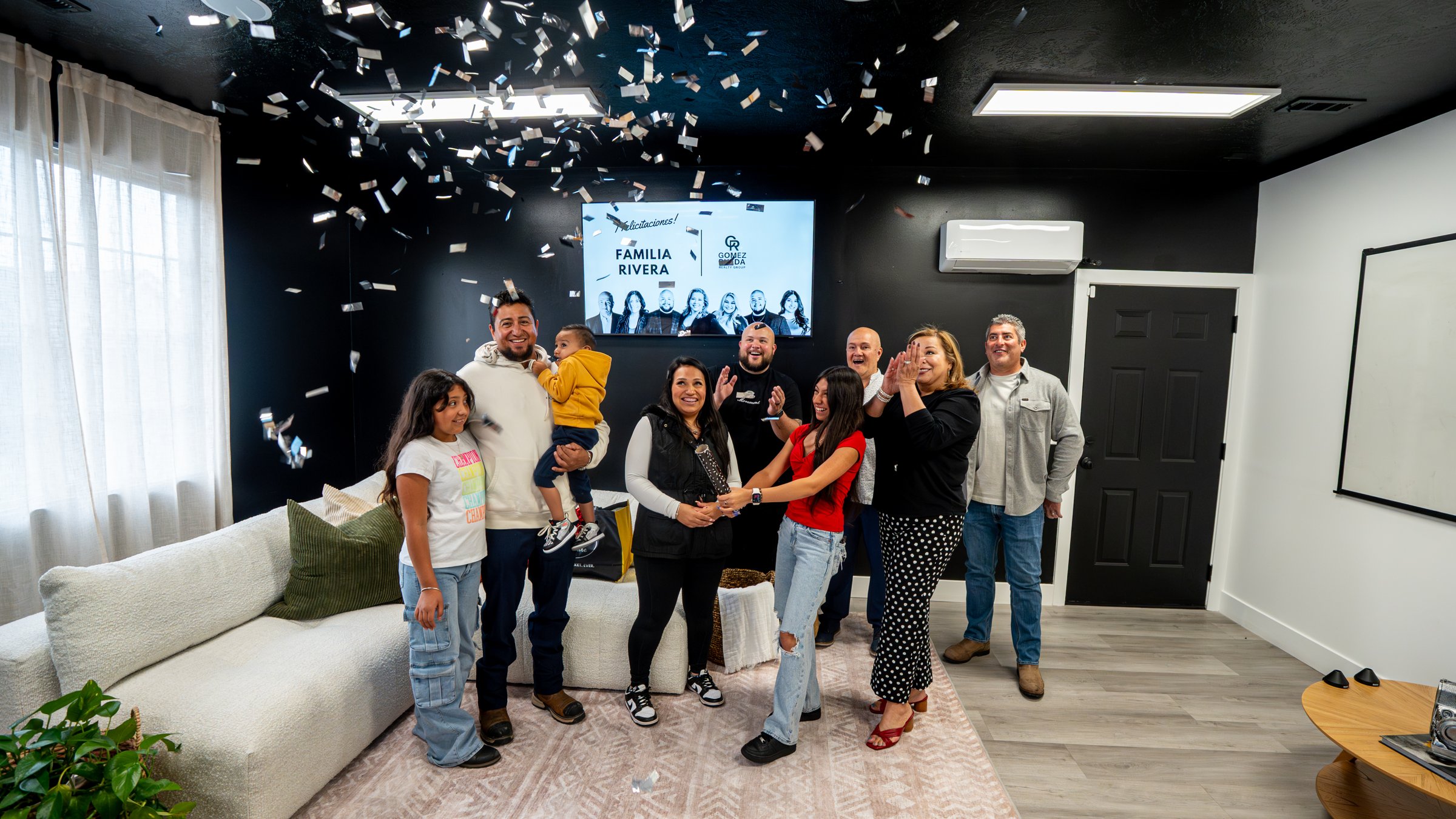 Una familia del condado de Salt Lake celebra el cierre de su casa con el equipo de GR Homes en la oficina de Gomez Rueda Realty Group en Taylorsville.